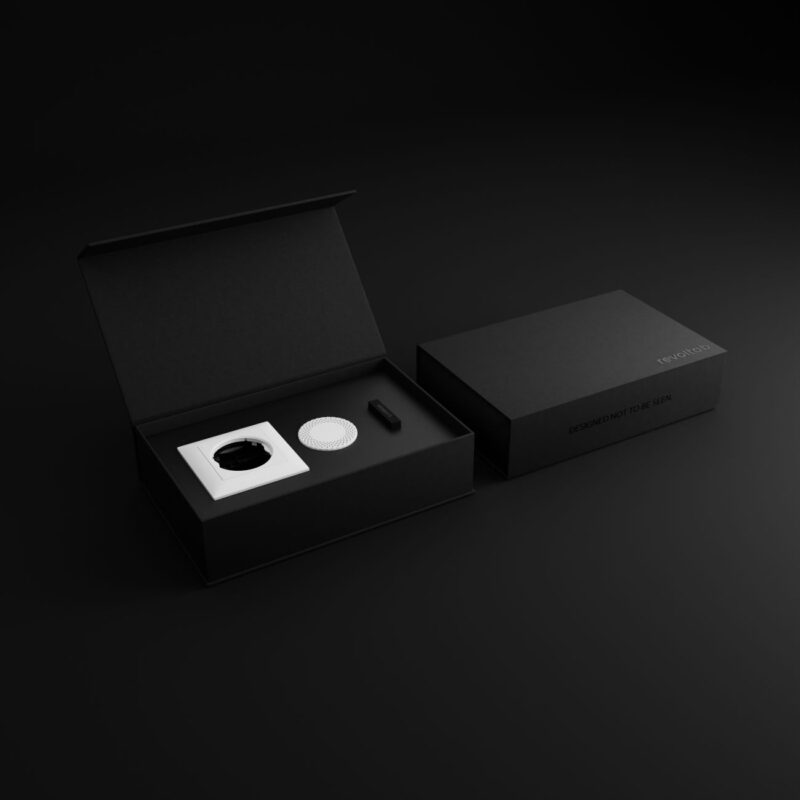 revoltab Starter Package white. You can see a black, open box, in which a smart diffuser and a white room fragrance tab.